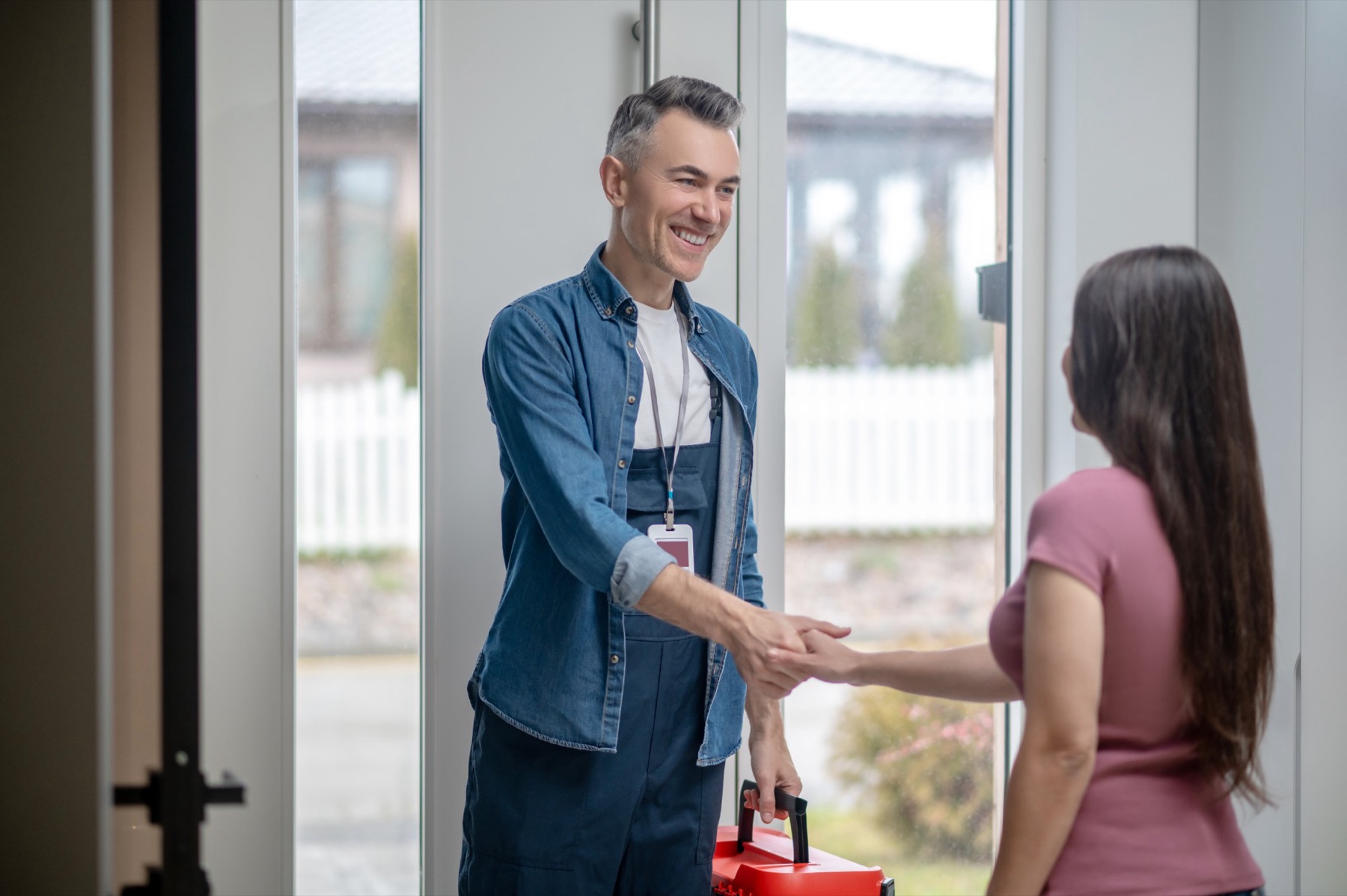 Un technicien serre la main d’une cliente sur le pas de sa porte